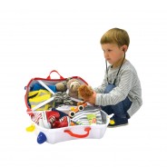 Kilkuletni chłopiec pakujący swoje zabawki do walizki na kółkach.