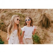 Dwie dziewczynki w okularach przeciwsłonecznych spacerują trzymając się za rękę.