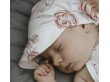 Śpiące niemowlę ma na główce chusteczkę z wiskozy bambusowej w kwiaty.