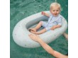 Maluszek w stroju kąpielowym siedzi w niebieskim pontonie.