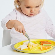 Mała dziewczynka je obiad z żółtego talerzyka.