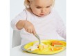 Mała dziewczynka je obiad z żółtego talerzyka.