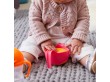 Dziecko korzystające z kubka niewysypka w kolorze różowo-pomarańczowym.