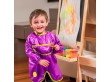 Chłopiec malujący farbami ma na sobie ochronny fartuszek w kolorze fioletowym.